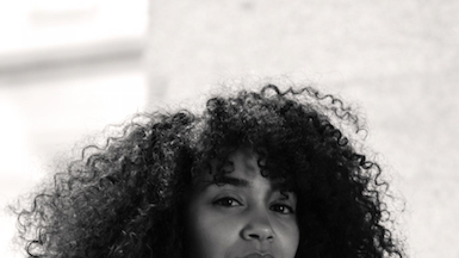 a black and white photo of a fair-skinned young woman with very long dark curly hair