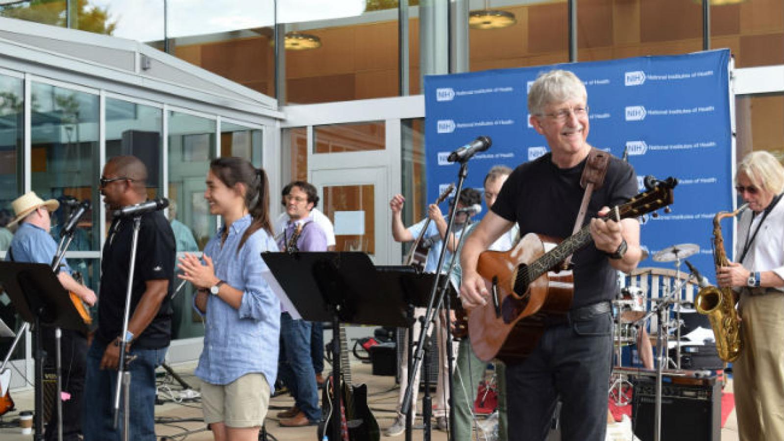 Man with white hair and mustache playing guitar with band