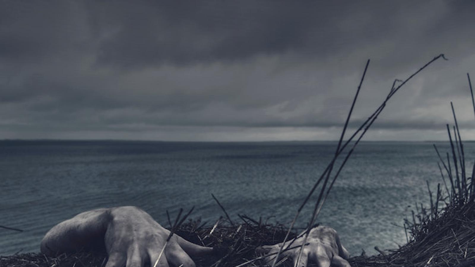 a pair of hands is the only visible part of a body that appears to be hanging from a cliff's edge