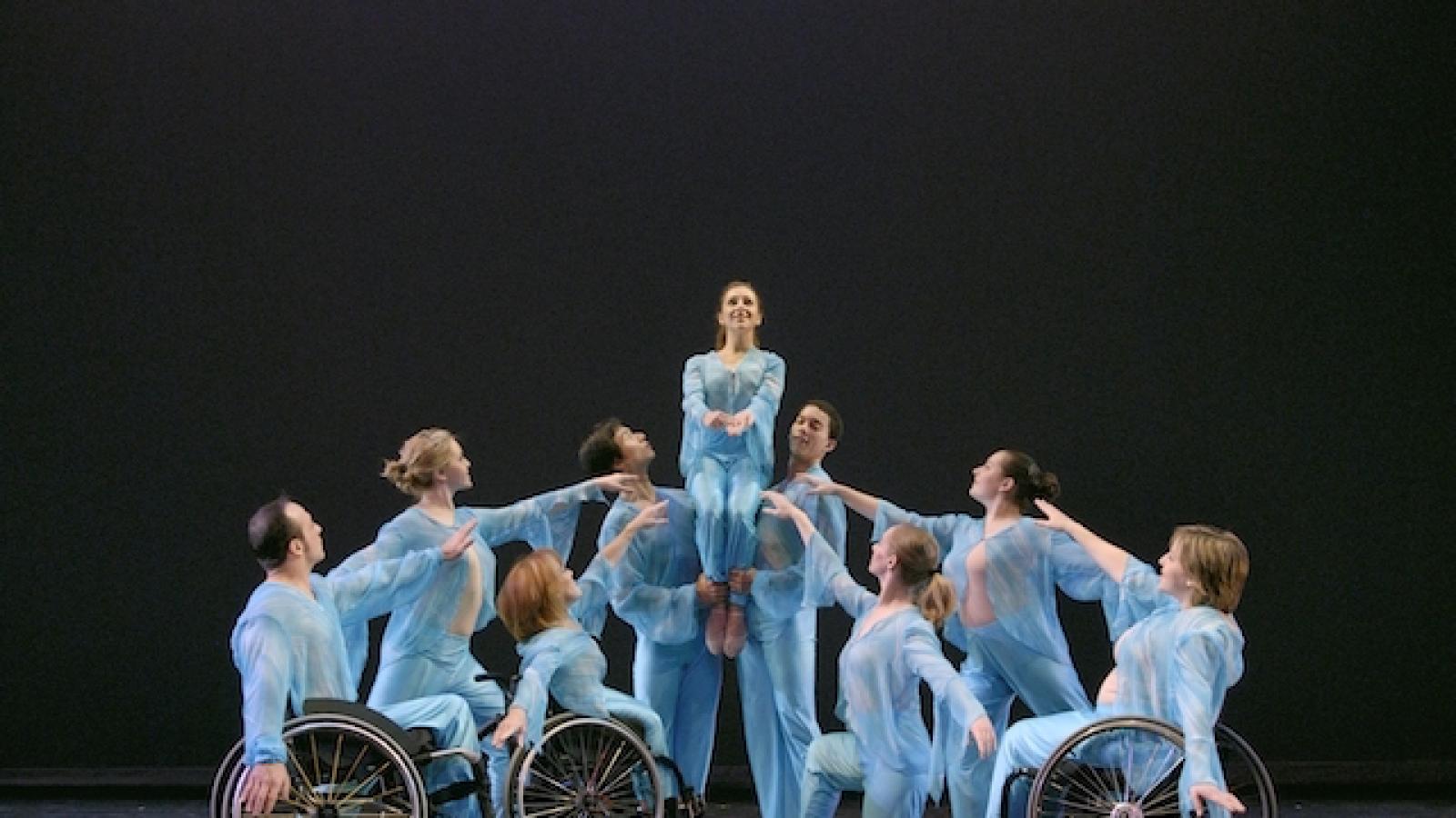 an ensemble of dancers some of whom are in wheelchairs performing on stage