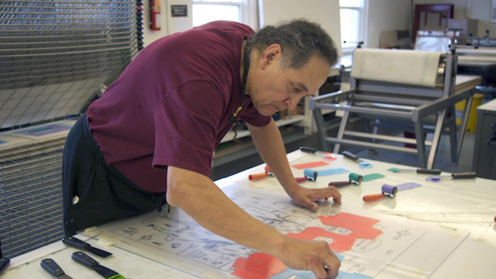 Artist Jim Denomie working in the printmaking studio at Crow's Shadow