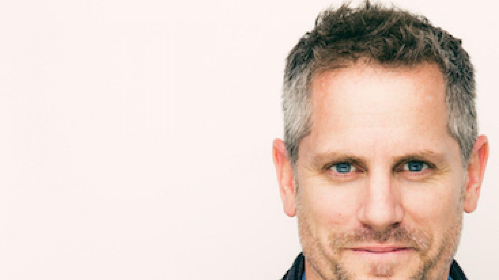 headshot of the actor Jonno Roberts a white man with short hair wearing a blue cardigan sweater