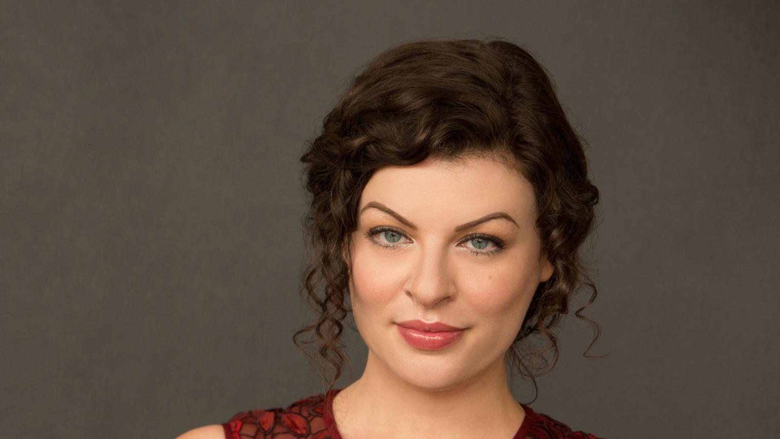 Head shot of woman with curly brown hair and sleeveless red dress