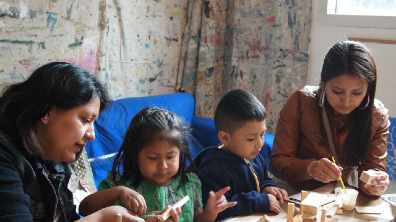 Two mothers building wooden sculptures with two children