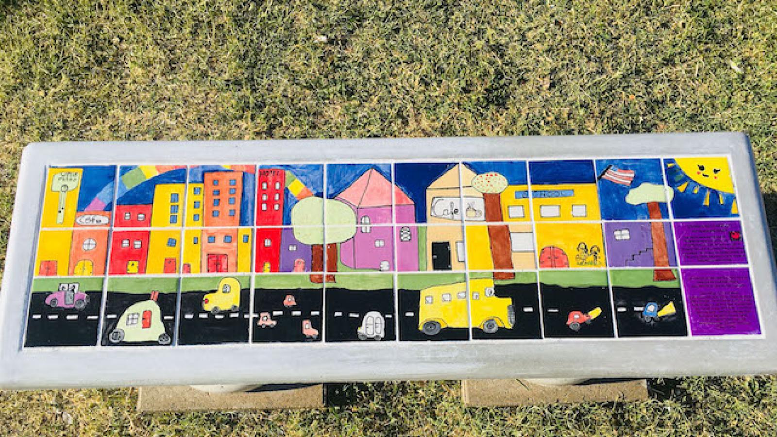 a colorful concrete bench decorated with children's drawings