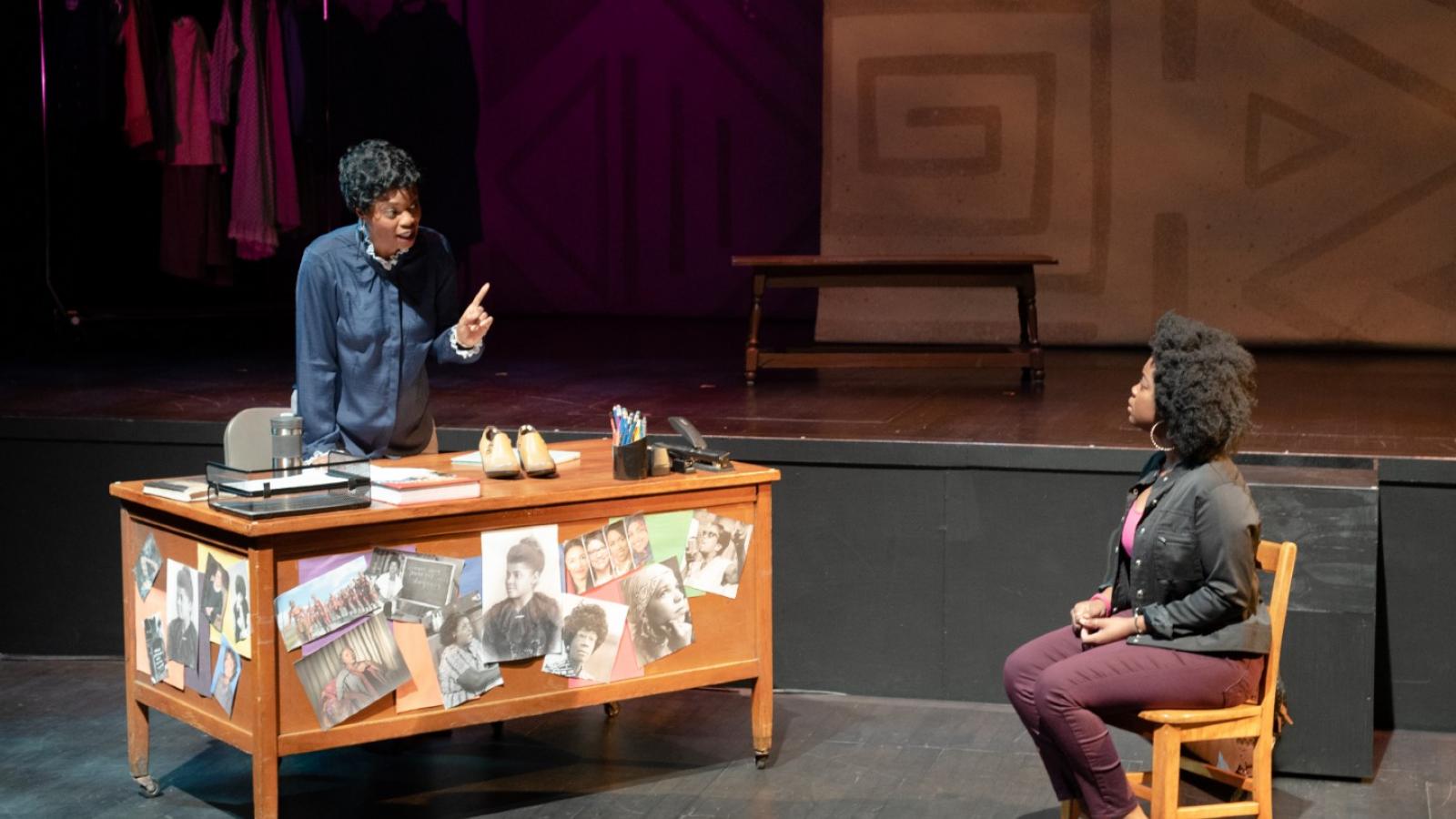 A scene from Lawbreakers! An actress plays the role of a teacher talking to a student from her desk