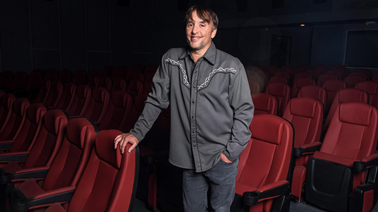 Richard Linklater Man standing while holding onto red theater seats