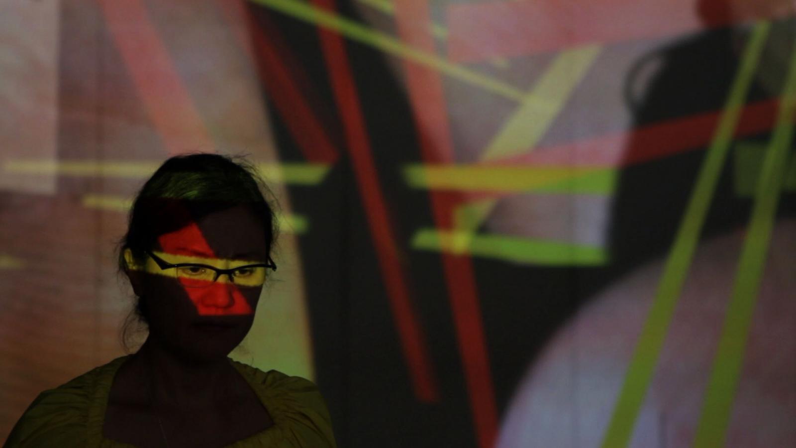 Woman in glasses with colored lights reflected on her. 