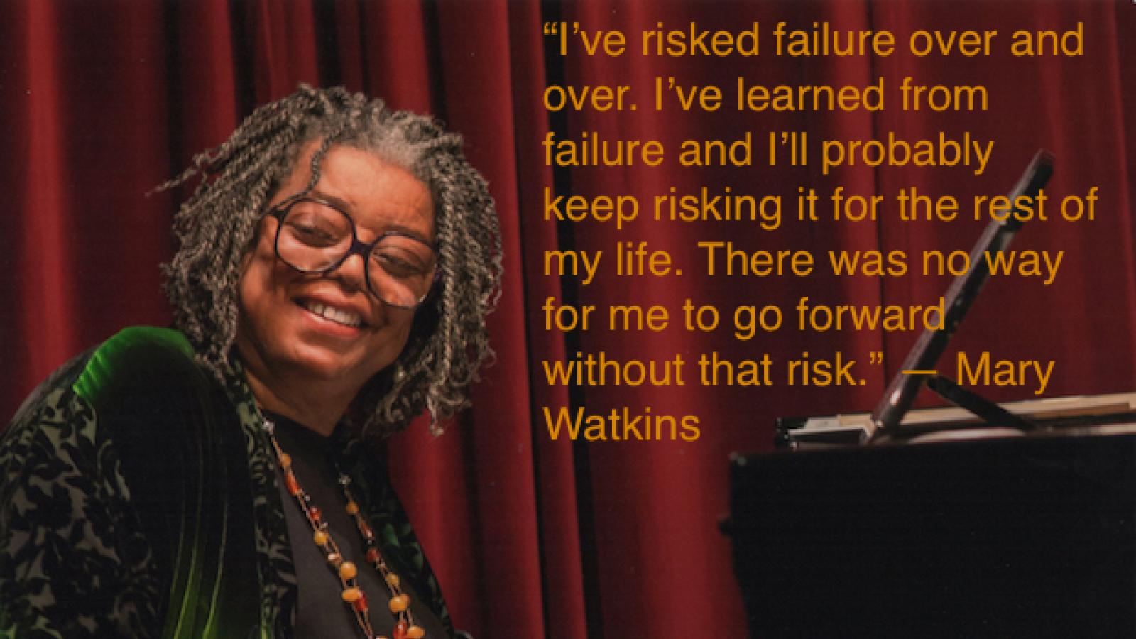 an older black woman with medium length locks and glasses sits at a black grand piano