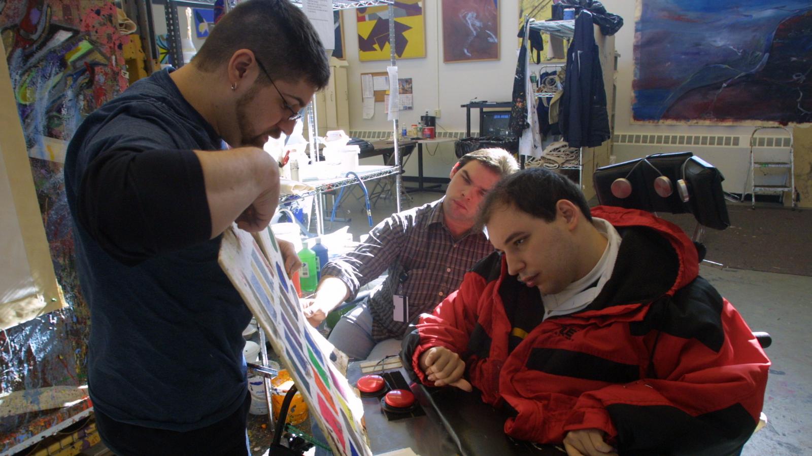 Man pointing to colors for man in wheelchair to choose.