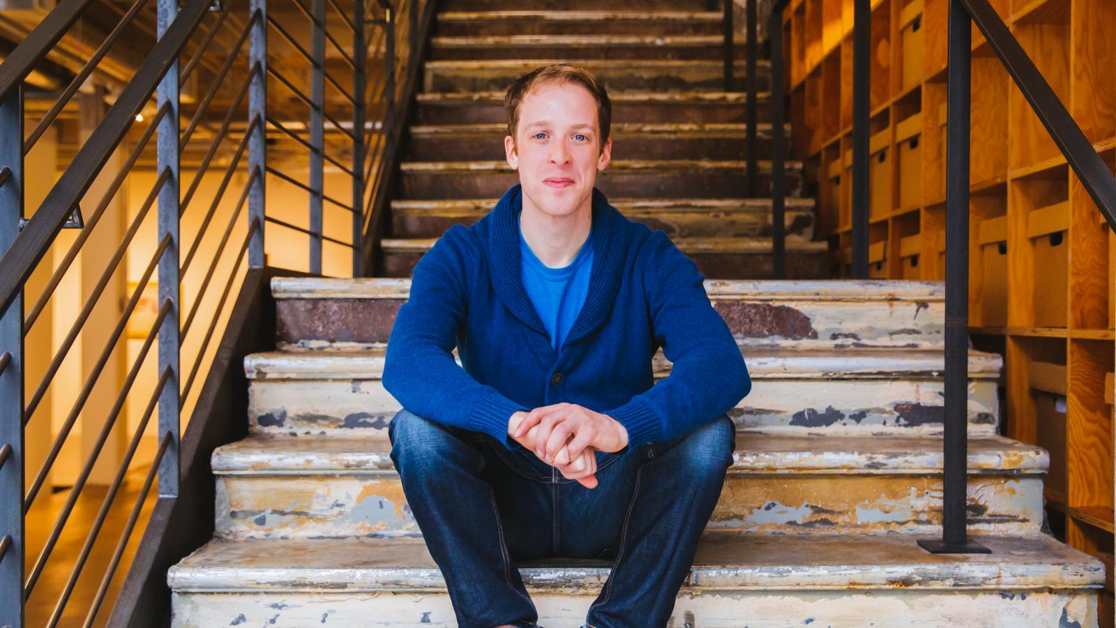 Mickey Rowe Man in blue shirt sitting on steps and looking at camera
