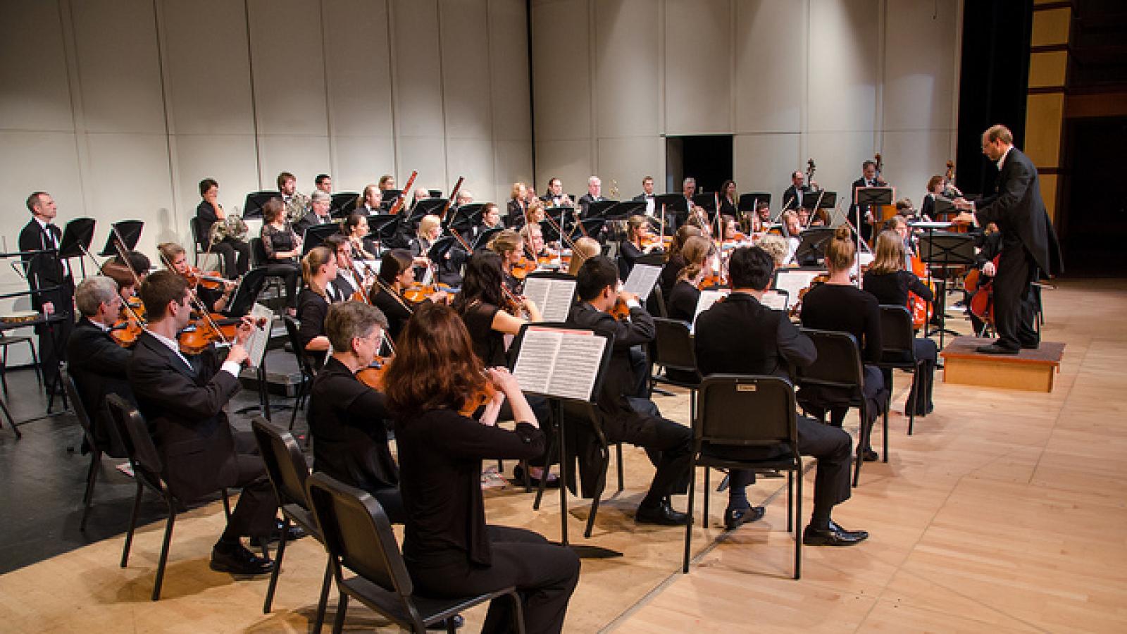 An orchestra sits on stage and performs