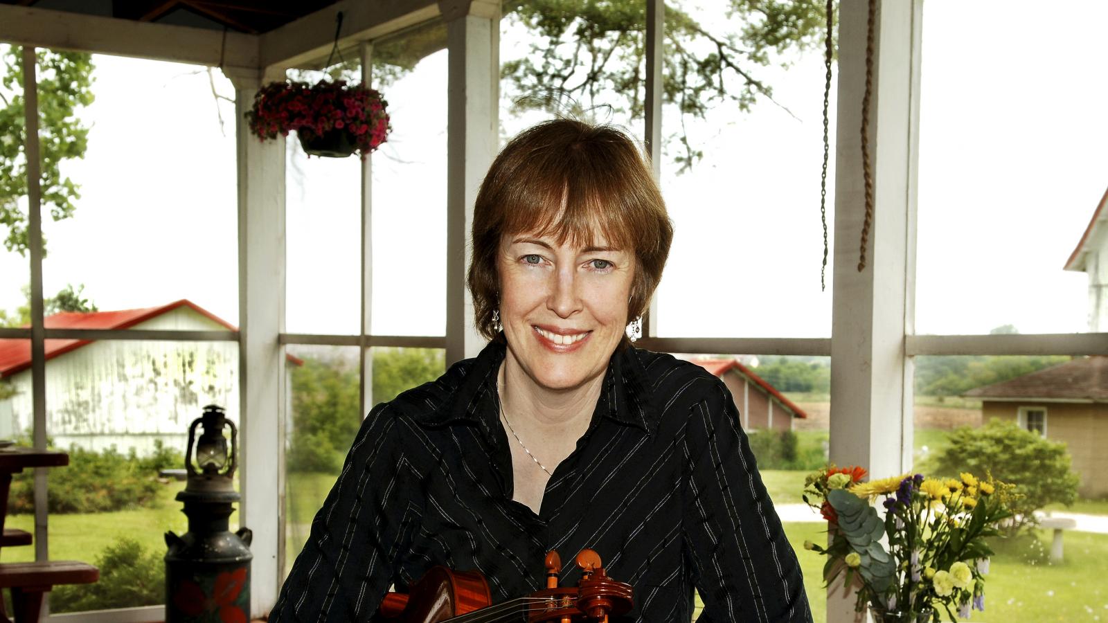 Woman in suit holding a fiddle. 