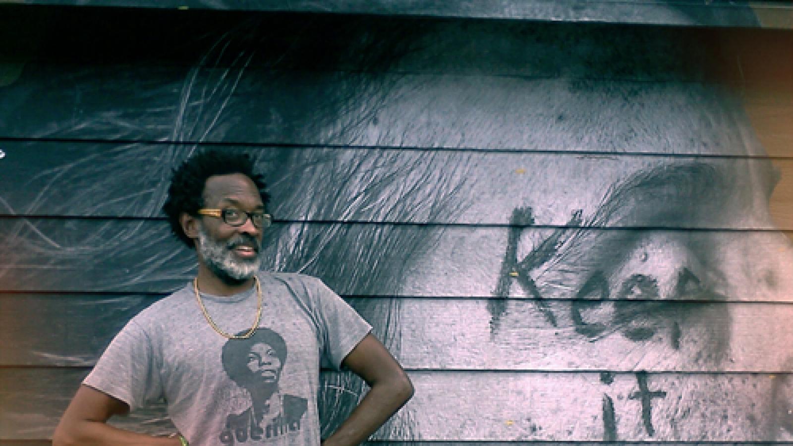 African-American man standing in front of his mural. 