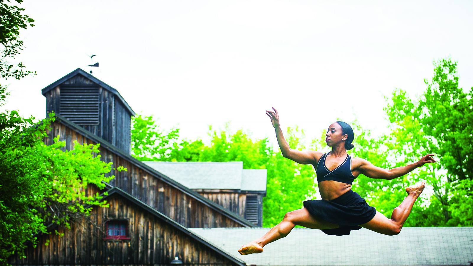 African-American dancer leaping in air before performing center.