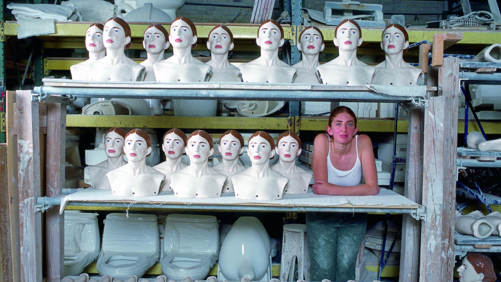 Woman standing with a bunch of ceramic renditions of her. 