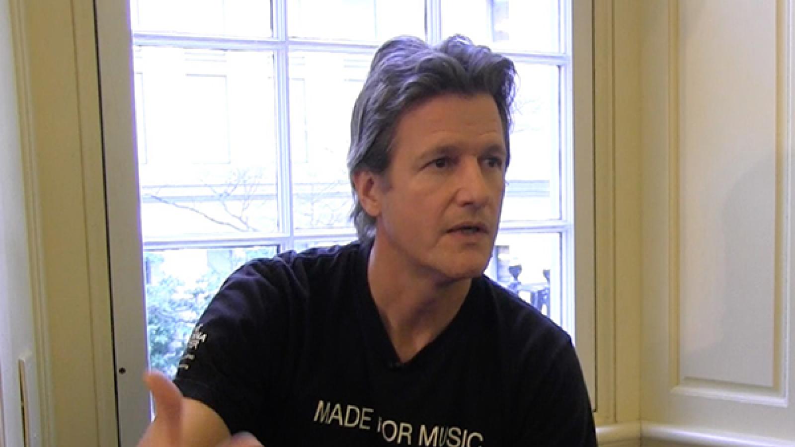 Man in black shirt gesturing with his right hand.