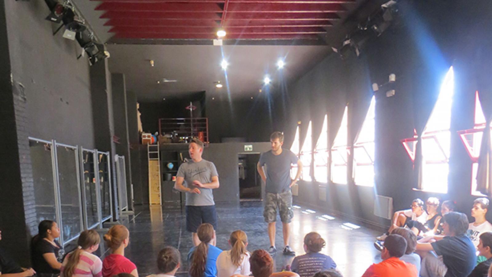 A theater class for teens Man standing and talking to group of seated teens