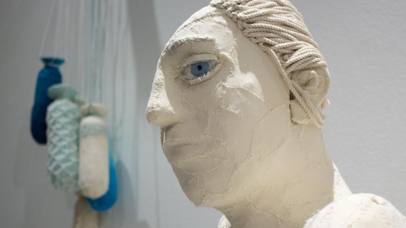 A white bust of a woman with one giant blue eye