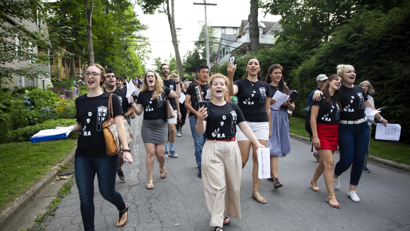 A group of young people sing as they march through a street