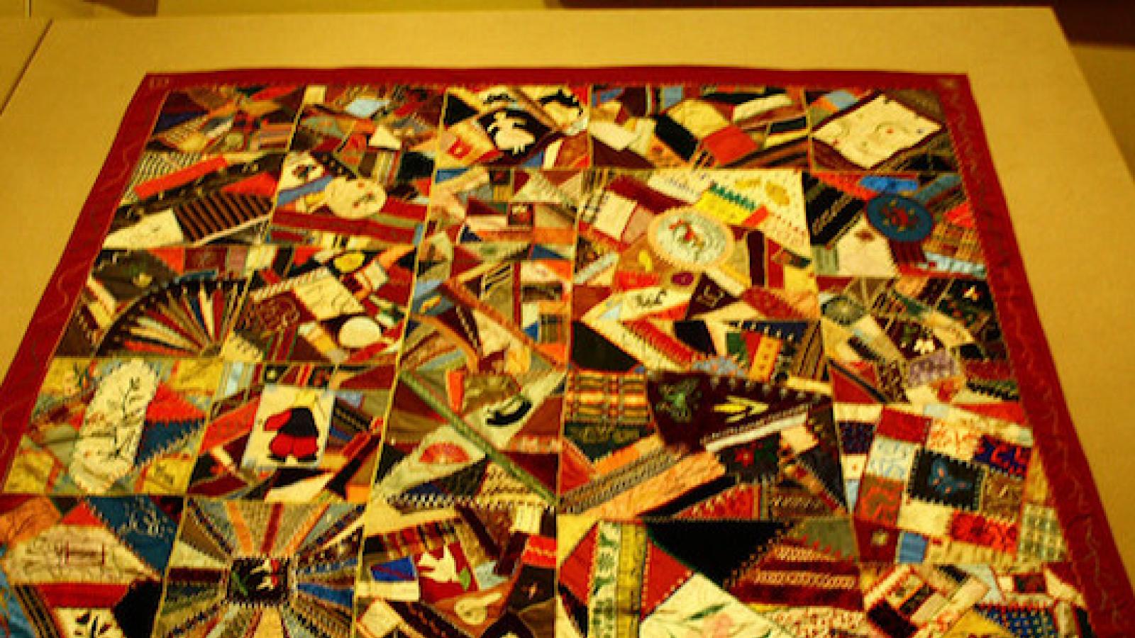 photo of a multi-colored pieced crazy quilt with a red border