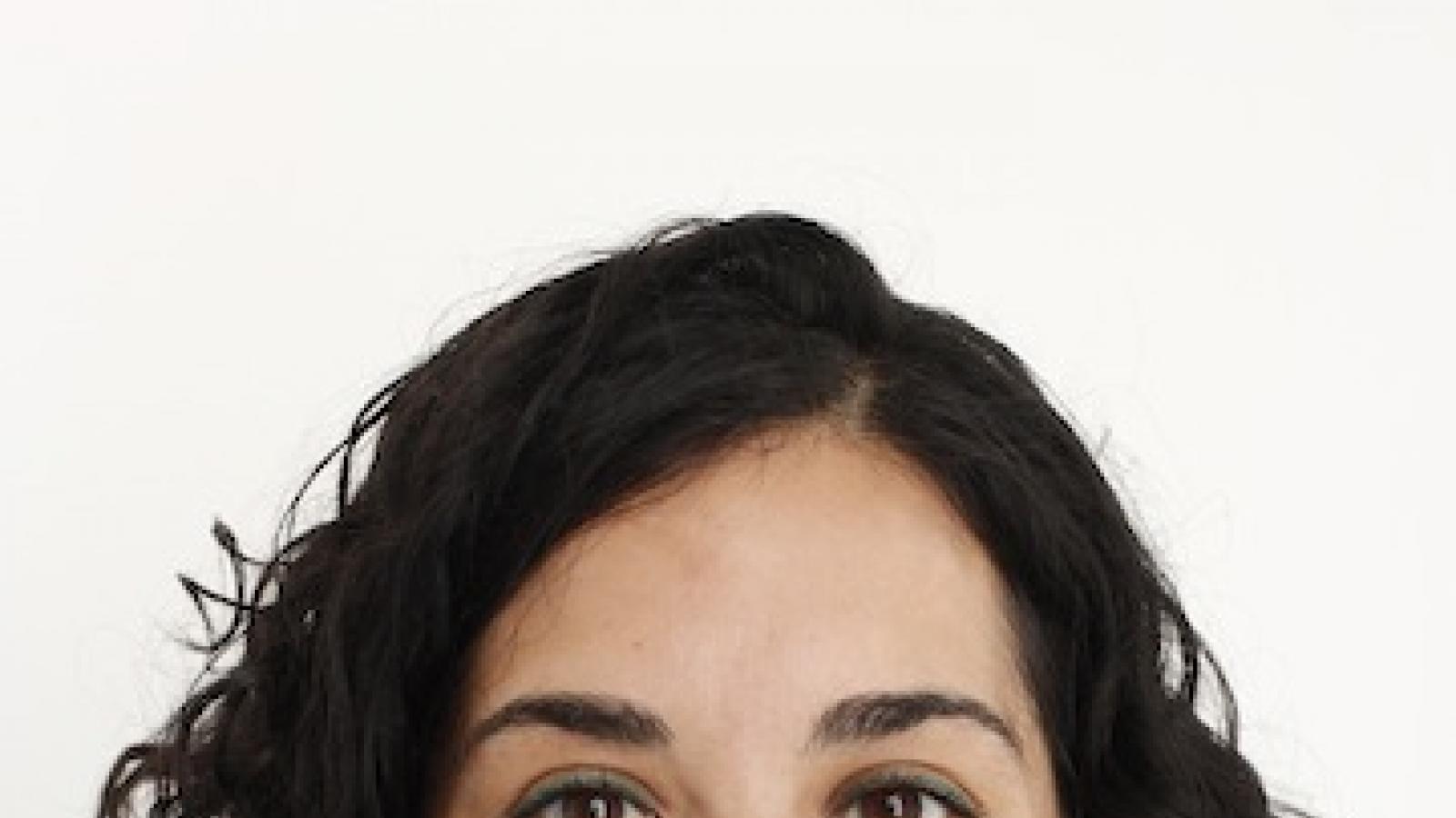 Headshot of a woman with dark hair and gold earrings