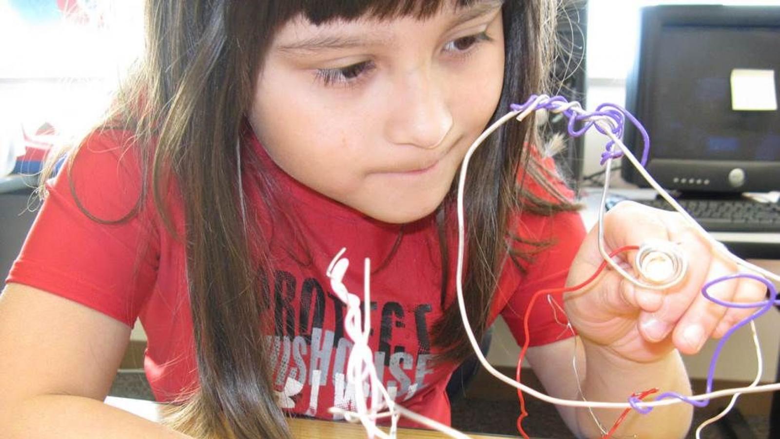 A second-grader at Quatama Elementary in Hillsboro, Oregon, lights the sculpture she created when a visual arts residency was integrated with the study of electrical circuits. Photo by Janis Hill