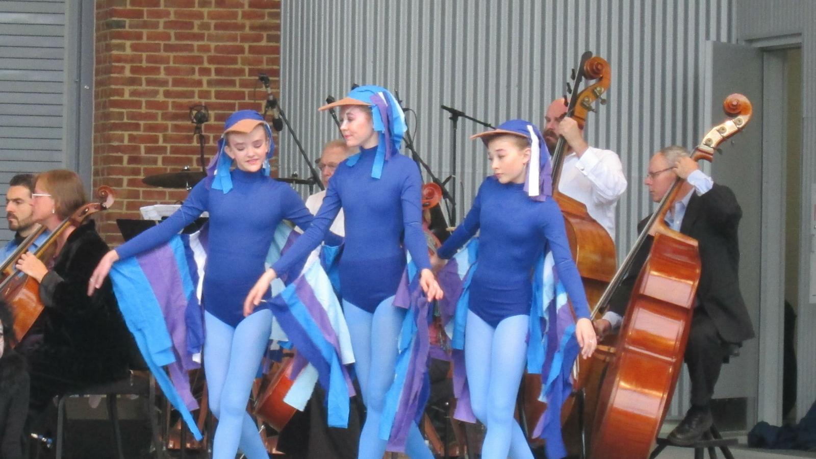 young dancers and orchestra musicians on stage