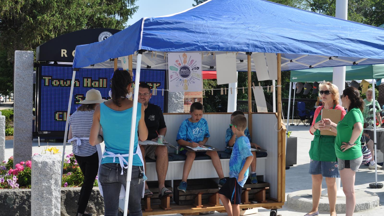 A family sitting in a booth making watercolor shoeprints of their feet