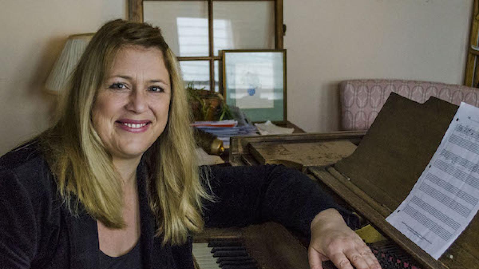 a blonde white woman casually sits at a piano