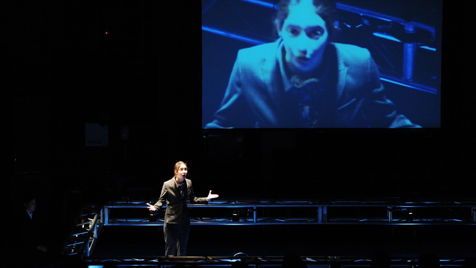 Woman on stage with screen behind her