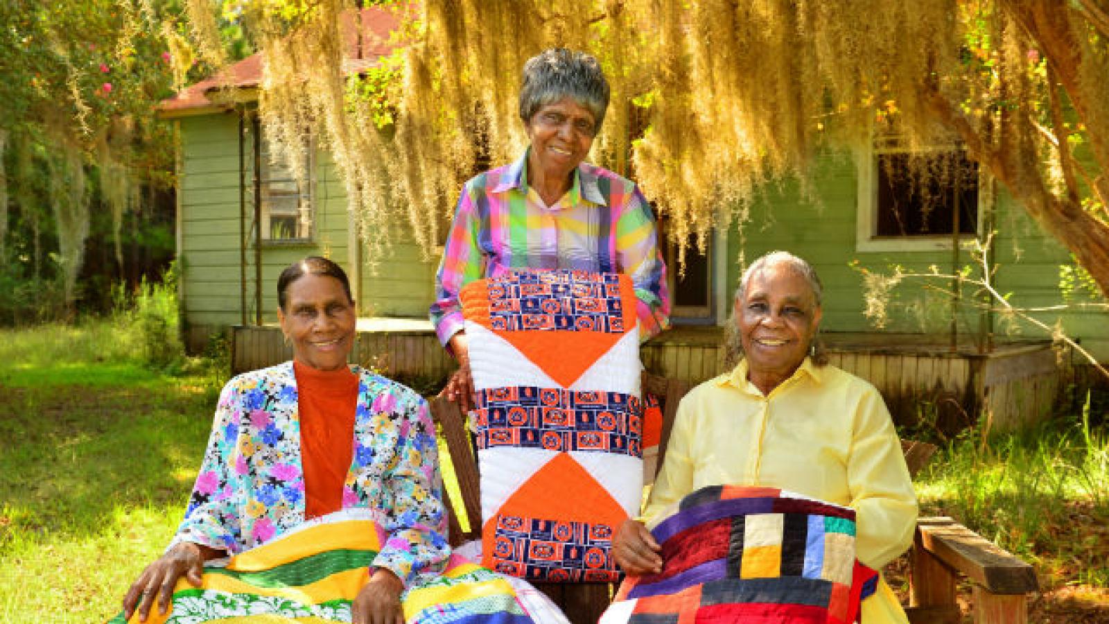Three African-American women holding quilts Three African-American women holding quilts