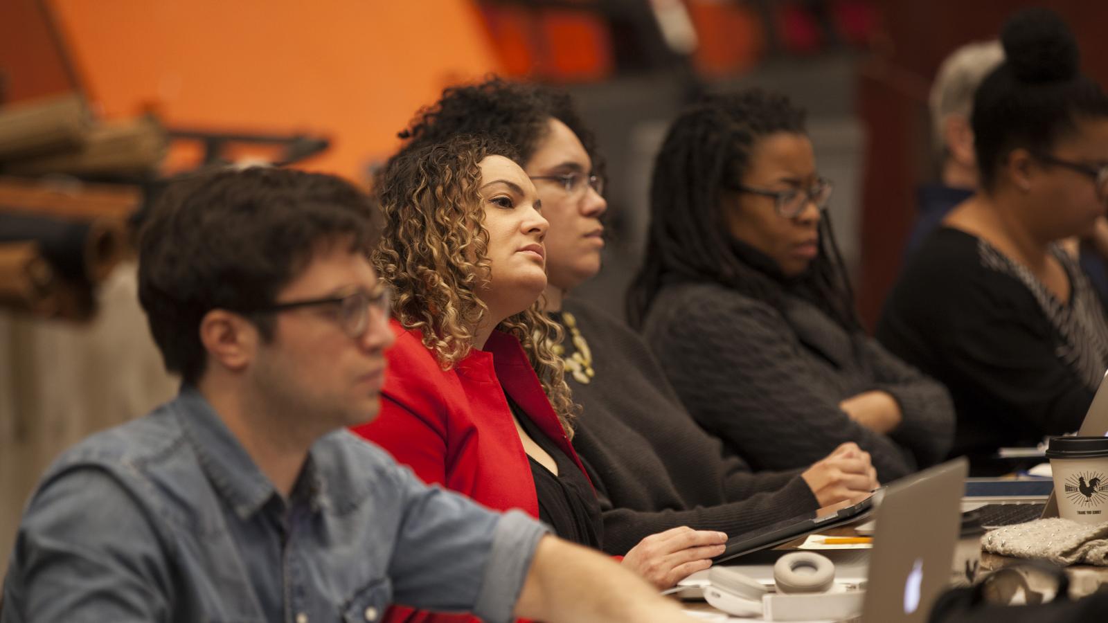 A group of men and women sit around a table during a reading of the opera Treemonisha