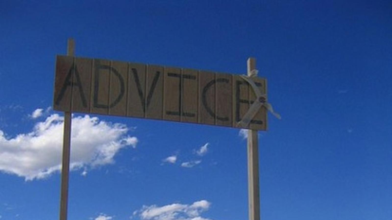 2 metal folding chairs under a banner that says "ADVICE' set amidst a desert landscape