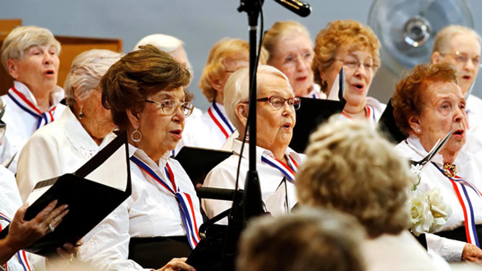 A group of older adult women singing in a chorus