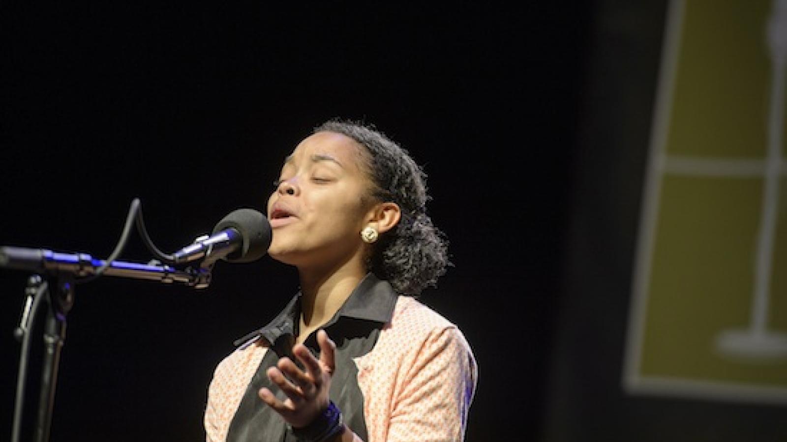 a young black woman is speaking emotively into a microphone 