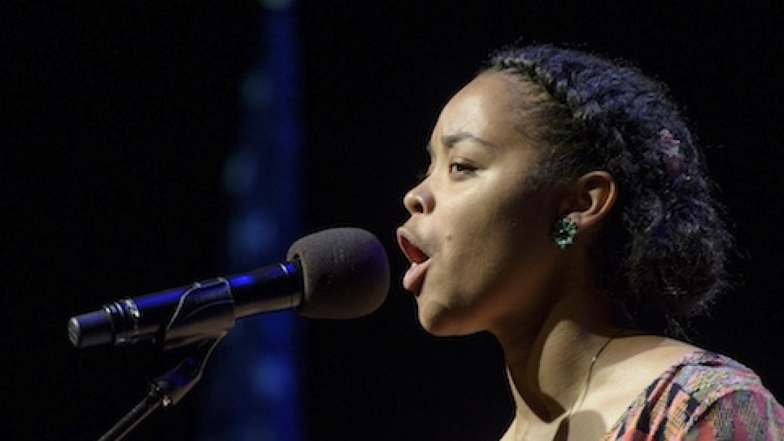 a young black woman  is speaking emotively into a microphone