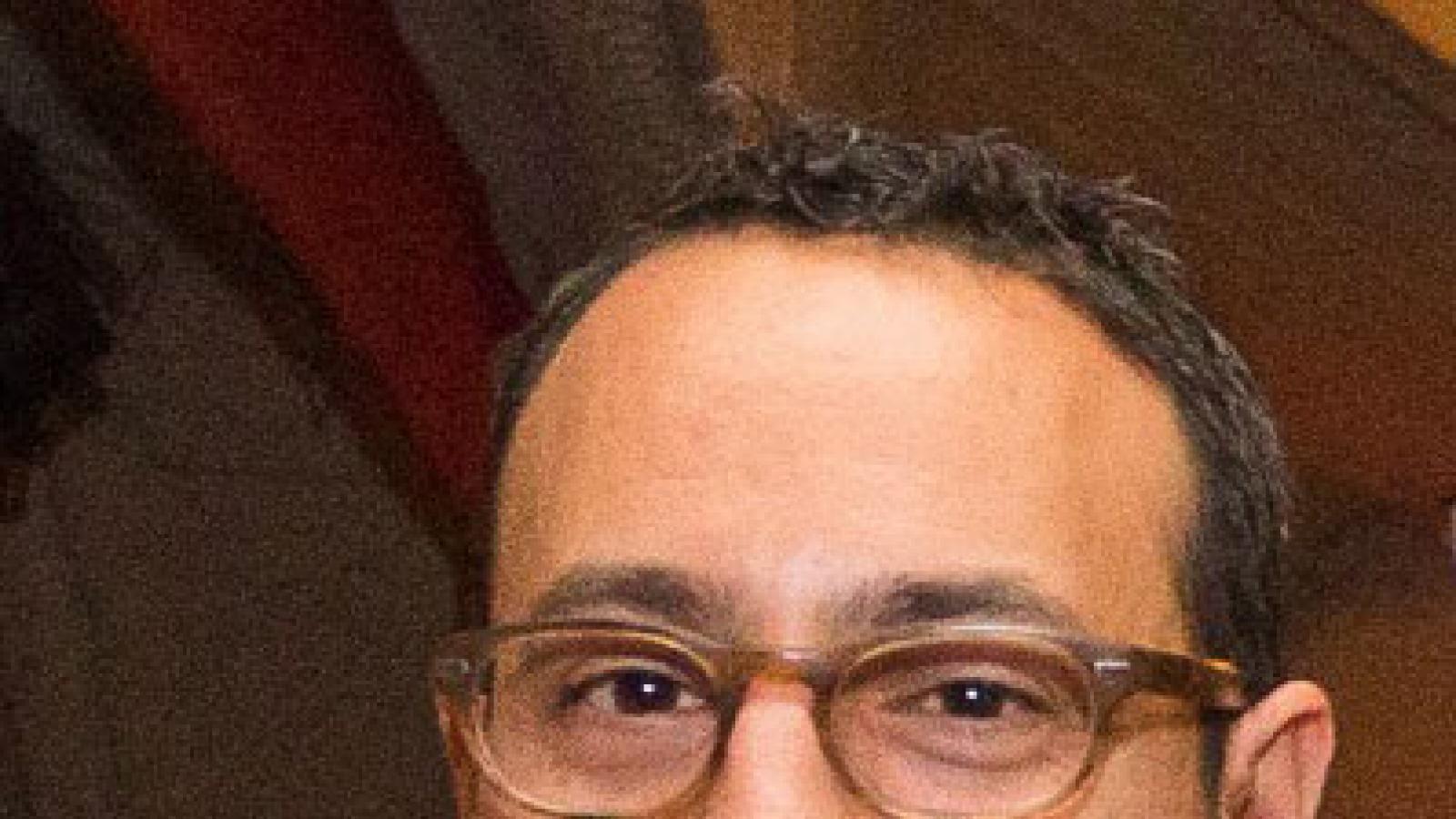 A headshot of a man with brown hair and glasses.