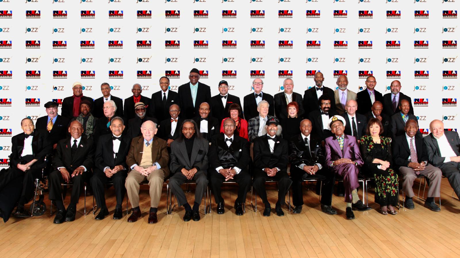 A group of men and women posing for a photo in front of a step-and-repeat.