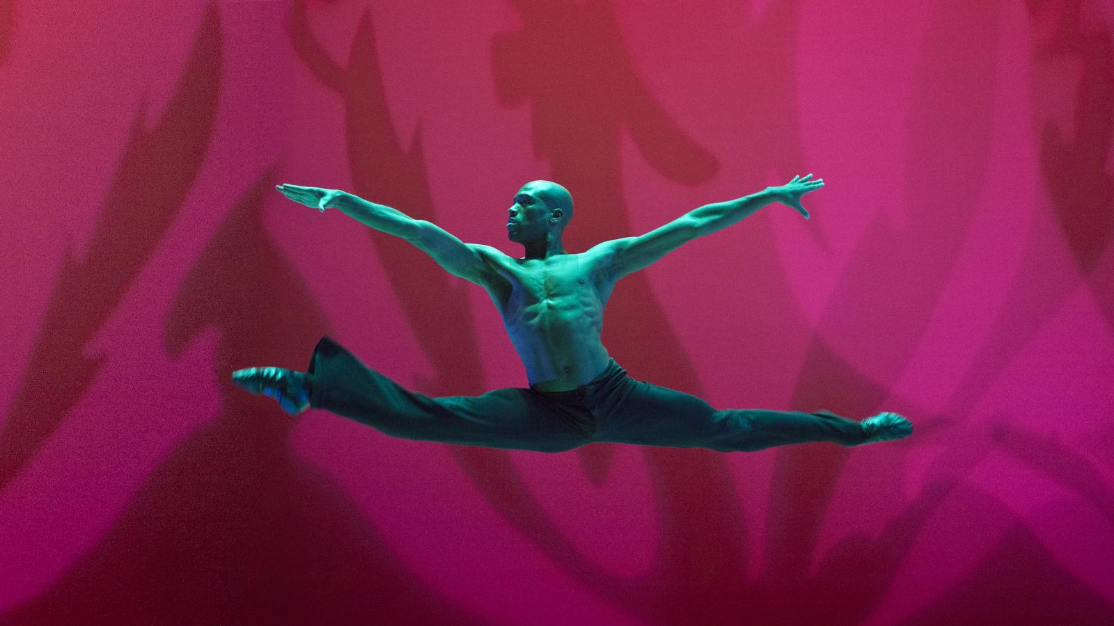 Man in mid-air with arms and legs extended during dance move. 
