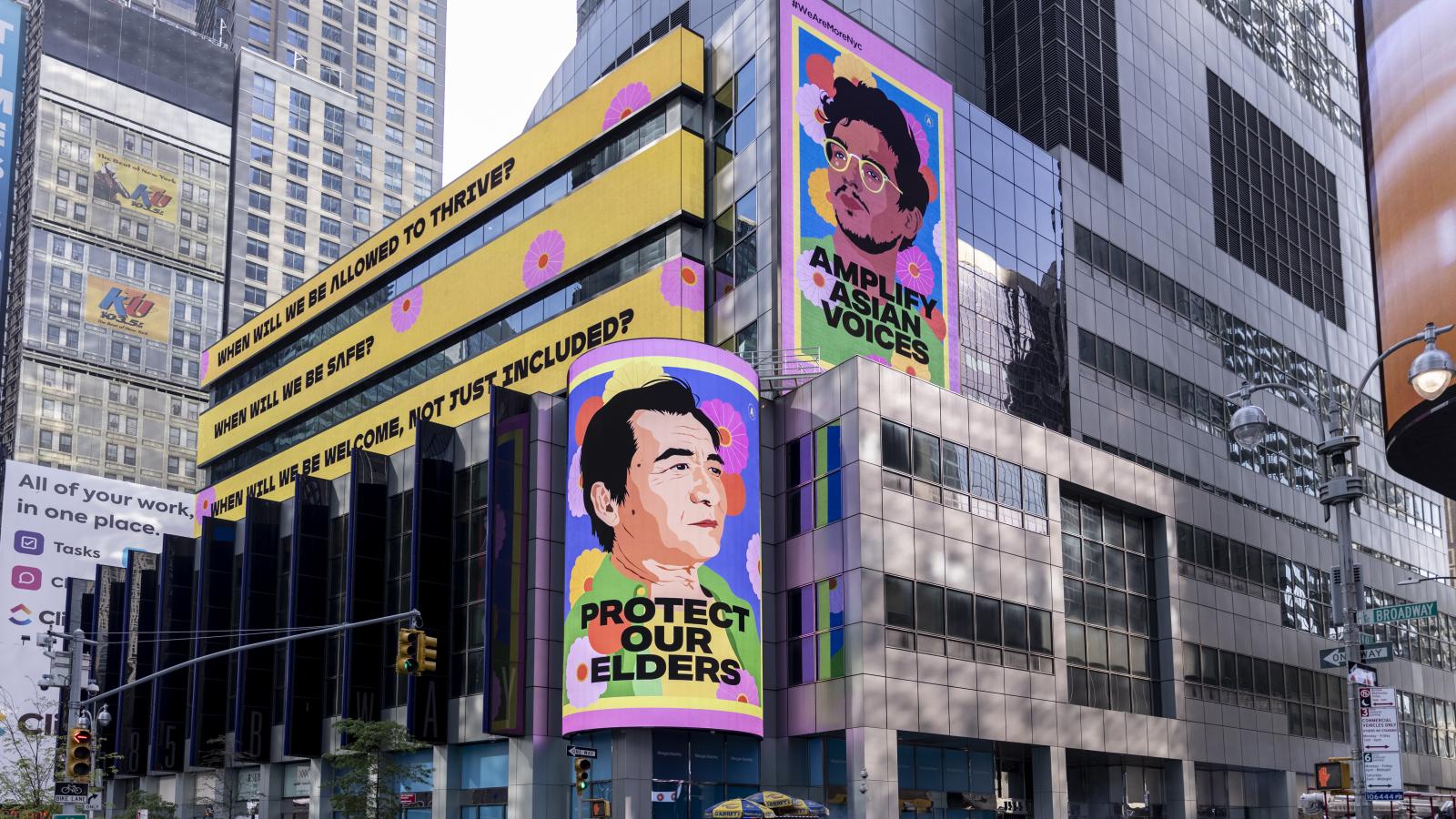 Street shot of Times Square in NYC with colorful posters of Asian men displayed. 