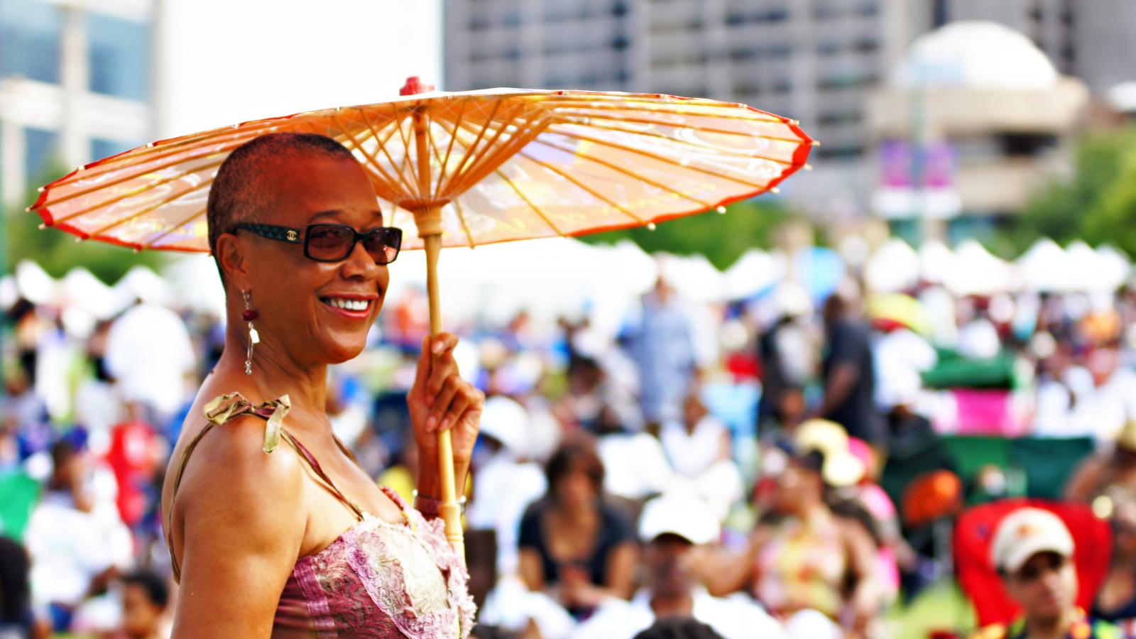 Woman standing outdoors at a festival holding a decorative umbrella.