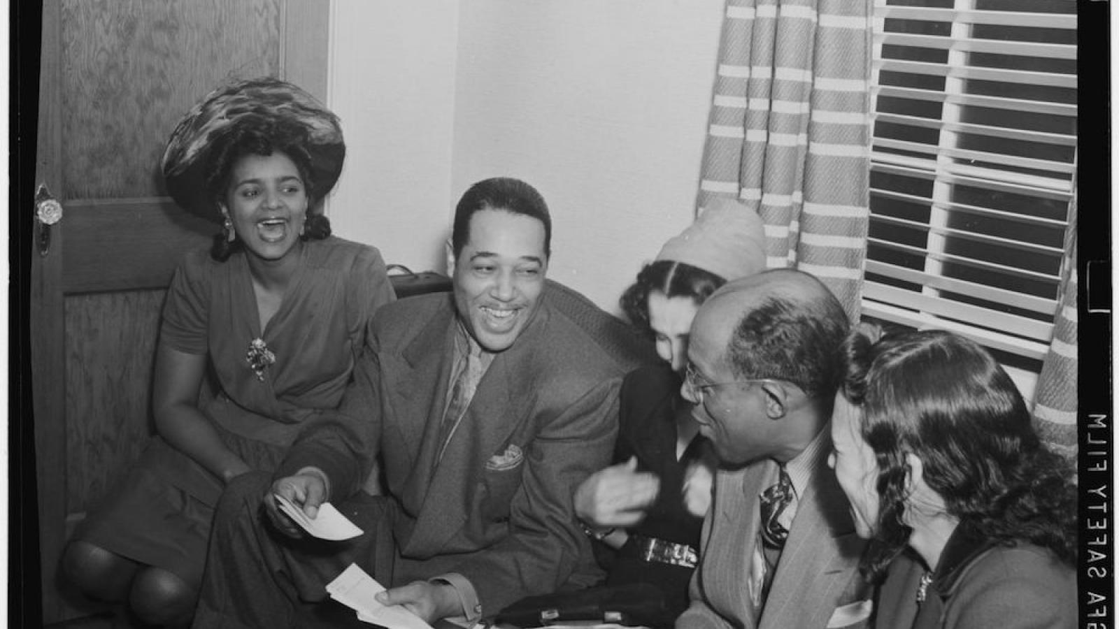 Duke Ellington sits with a group of friends on a sofa in William Gottlieb's home