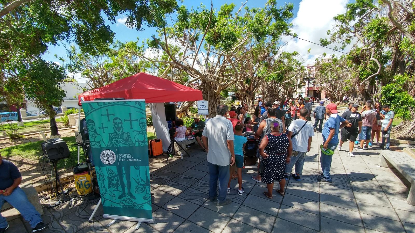 A group of people milling around a tree-lined plaza. 