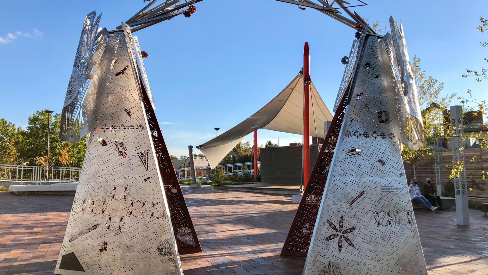 Public sculpture of large metal triangles connected on top by a series of triangles.