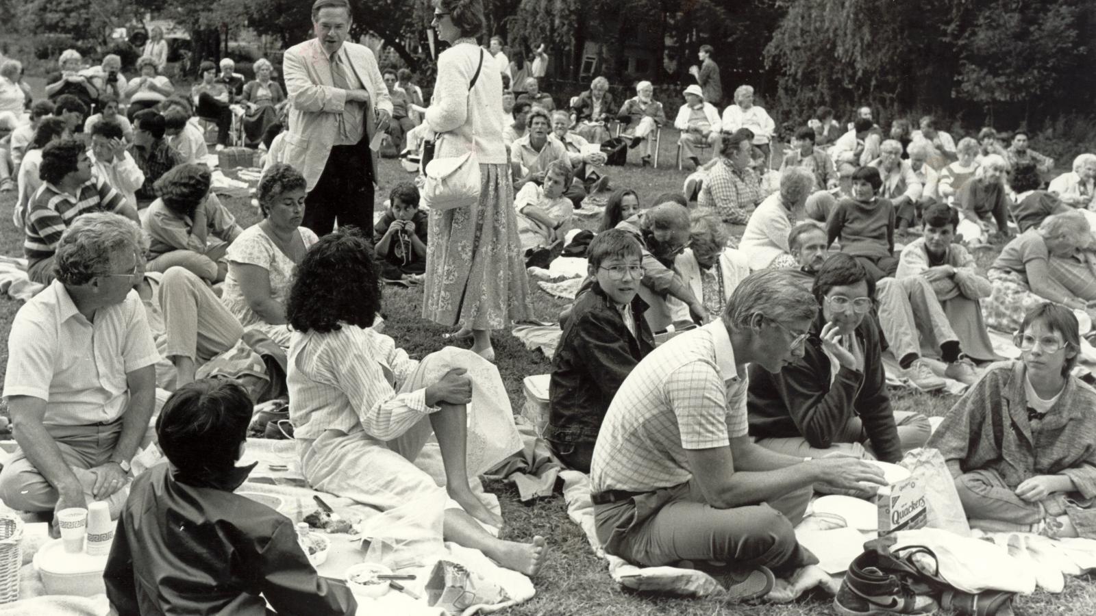 Crowd sitting on lawn for play.