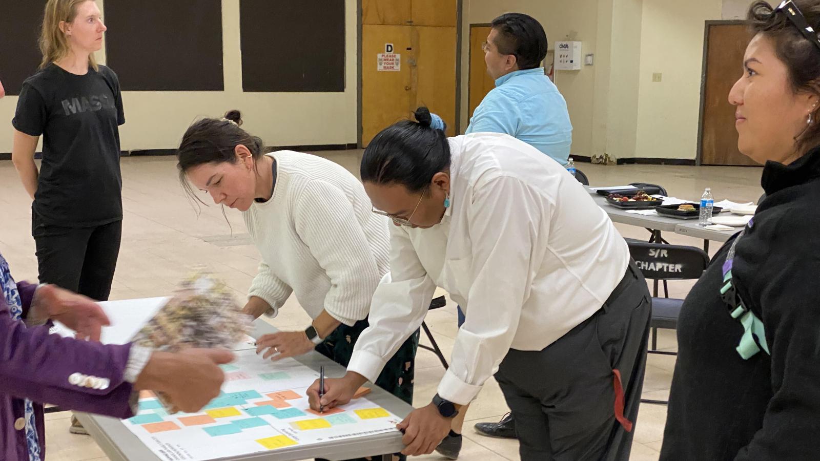 A group of people leaning over a table with papers on it.