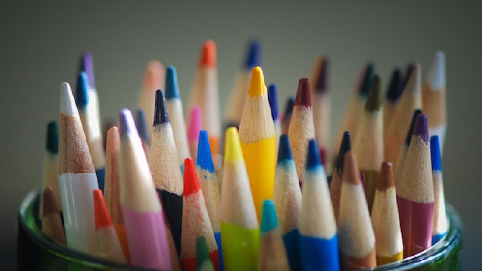 a bunch of colored pencils in a container with their tips facing up