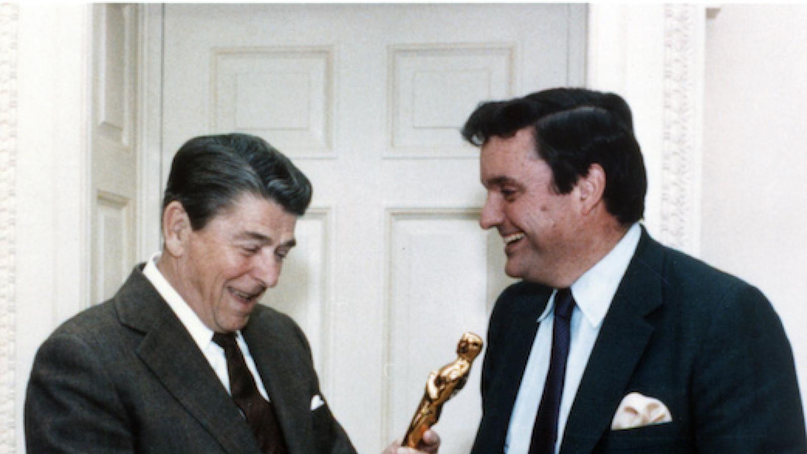 President Ronald Reagan holds an Oscar statuette while Frank Hodsoll looks on