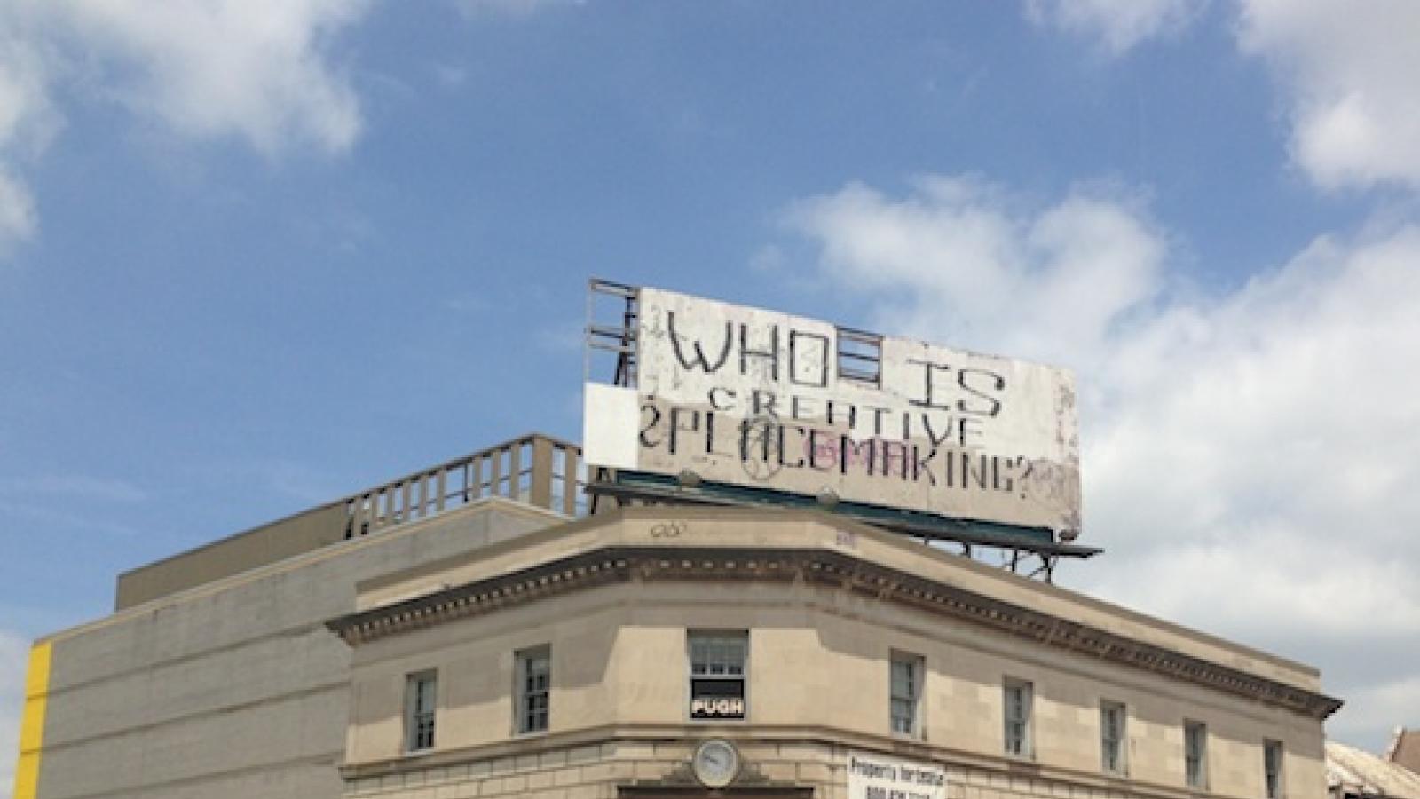 an older building with a billboard that says "Who is Creative Placemaking?"